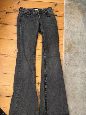 Grå bootcut jeans med fickor - Säljer ett par grå bootcut jeans med klassisk femficksdesign och snygga detaljer på bakfickorna. Jeansen har utsvängda ben och normal midja. Perfekta för dig som gillar en retroinspirerad look och vill ha något som sticker ut lite extra. Nypris 400 