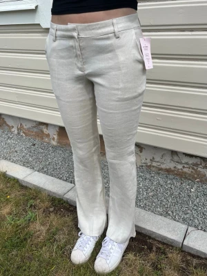 Nelly Linnebyxor Low Waist Flare – storlek 36 – NYA med prislapp - Nya med prislapp.  Beiga linnebyxor från Nelly, modell Low Waist Linen Flare Pants. Storlek 36. Modellen är 180 cm, och byxorna något korta. Passar ca 175 cm i längd. 52% linne, 46% viskos, 2% elastan. Perfekta till sommaren. Aldrig använda, inga defekter.