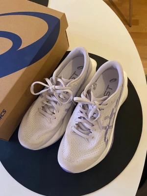 Löparskor från Asics - Säljer ett par stilrena ljuslila löparskor från Asics med ventilerande mesh-ovandel och dämpad sula med FF Turbo-teknologi. Skorna har klassisk snörning och diskreta lila detaljer på sidan. Skorna har endast använts två gånger och är i toppskick. 
