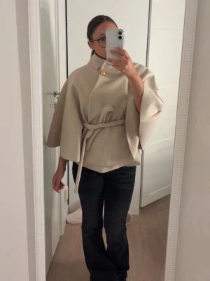 Beige cape-kappa från Missay - Jätte fin beige poncho-kappa från Missay. Har haft på mig en enda gång. Säljer då den inte riktigt känns som min stil. Pris kan diskuters!💕