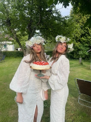 Vit adoore liknande långklänning med volangärm - Superfin vit långklänning med v-ringning, puffiga volangärmar och knappar framtill. Klänningen har slits och ett diskret blommigt mönster i tyget. Perfekt för sommarens alla tillfällen! Köpt på plick men aldrig använd, saknar märke inuti men liknar adoore på pricken enligt mig.