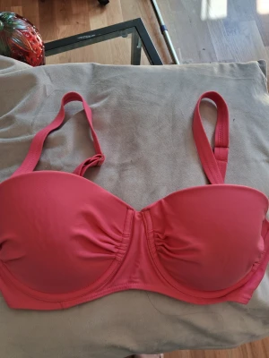 Rosa vadderad baddräktöverdel - Trendig rosa baddräktöverdel med vadderade kupor och bygel för extra stöd. Justerbara axelband och lätt rynkade detaljer framtill. Tillverkad i ett slätt, stretchigt material som känns bekvämt mot huden. Liten metallogo på ena sidan för en snygg touch.