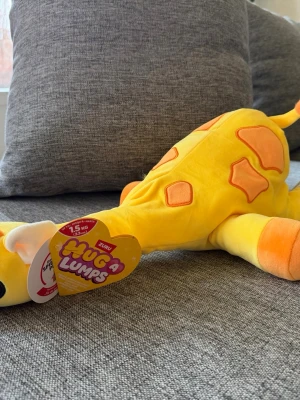 NY! Hug A Lumps Giraff 1,5kg Gigi Zuru Gosedjur - Zuru Hug A Lumps gosedjur i form av en giraff. Denna mjuka giraff är designad för att kramas med och har en vikt på 1,5 kg. Lämplig för åldrar 3 och uppåt.  Ny i kartong!