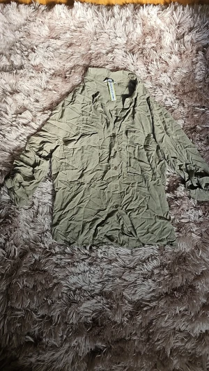 Olivgrön overshirt med fickor - Säljer en olivgrön overshirt med knappar framtill och två bröstfickor. Skjortan har en avslappnad passform och är gjord i ett mjukt, tunt bomullstyg. Perfekt att bära öppen över en t-shirt eller stängd för en mer klassisk look. (Har ej strukit den, men är finare struken!) Är storlek XL men passar M,L.
