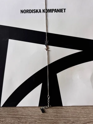Silverhalsband från Saint Laurent - Snyggt och stilrent halsband i silverfärgad metall från Saint Laurent. Halsbandet har en tunn kedja och ett ikoniskt YSL-logotyp-hänge i mitten. Justerbar längd med liten bricka där det står 'Saint Laurent Paris'. Perfekt accessoar för att lyfta din outfit.