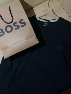 Marinblå tröja från BOSS - Snygg mörkblå tröja från BOSS med rund halsringning och diskret logga på bröstet. Tillverkad av italienskt garn för en lyxig känsla. Perfekt för dig som gillar stilrena och klassiska plagg. Pris kan diskuteras.