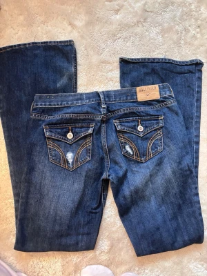 Blå bootcut jeans från Hollister - Low waist bootcut jeans from hollister W26 L31. No photos on bc theyre too big, theyre a bit damaged on the bottom. I cant put more photos so ask if u wanna see