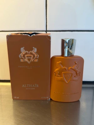 Parfums de Marly Althaïr EdP 125ml - Parfymen rymmer 125ml och skulle nog uppskatta och säga att det är ca 114ml kvar. Inget fel med parfymen. Kartongen däremot har gått igenom en massa😅 allt som syns på bilden skickas hem! Har du fler funderingar är det bara att skriva till mig!