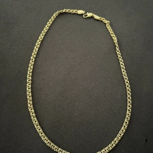 Bismarck halsband 45mm - Stilrent halsband i guldfärgad metall med en klassisk kedjedesign. Halsbandet har en enkel karbinhake och passar perfekt för att lyfta vilken outfit som helst. Kedjan har en rundad form och ger ett elegant intryck.