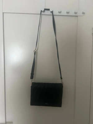 Svart axelväska från Ulrika - Säljer en elegant svart axelväska från Ulrika Sweden. Perfekt till både vardag och fest tack vare sin tidlösa och minimalistiska design.