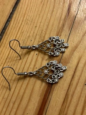 Vackra örhängen - Dinglande örhängen i silvrig metall med glittrande stenar.