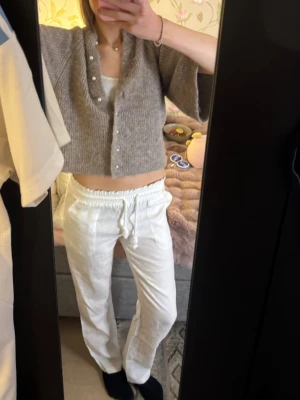 Vita linnebyxor med snörning  - Säljer ett par vita linnebyxor med avslappnad passform och elastisk midja med snörning. Byxorna har raka ben och är tillverkade i ett lätt och luftigt linnetyg, perfekta för en chill och stilren look.