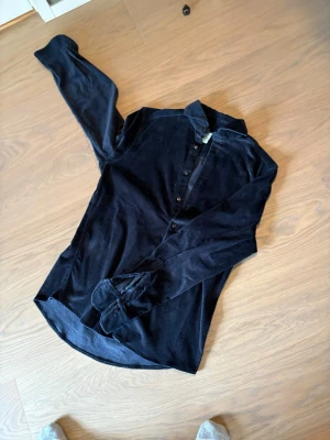 Svart manchester skjorta stenström - Säljer en svart henley skjorta i mjuk manchester med lång ärm och knappar framtill. Skjortan har en klassisk krage och är perfekt för dig som gillar en avslappnad men ändå stilren look.Andra stenströms skjortor i detta skick ligger på runt 600,