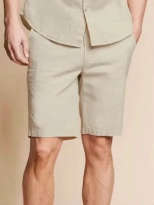 Beige linneset med skjorta och shorts - Snyggt och luftigt set i beige linne med kortärmad skjorta och matchande shorts. Perfekt för varma dagar och ger en clean, avslappnad look. Skjortan har knappar framtill och shortsen har sidfickor. Använd vid ett tillfälle 