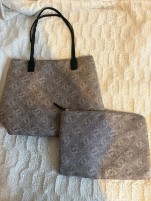 Två stycken väskset  - Säljer ett snyggt och stilrent väskset i beige. Setet består av en stor väska som är prefekt för vardag eller jobb samt en liten mindre fodral/väska som passar t.ex dator, surfplatta eller mindre saker. Skicket är väldigt fint 