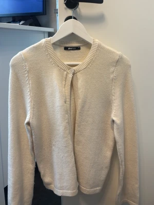 Krämvit kofta från Gina Tricot - Säljer en krämvit kofta från Gina Tricot med rund halsringning och en knapp framtill. Koftan har långa ärmar och ribbade muddar vid ärmslut och nederkant. Perfekt att slänga över en topp för en enkel och clean look. Inget fel på varan bara att den använts några gånger. 
