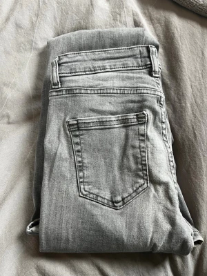 Grå jeans från ONLY, storlek 32 - Säljer ett par grå jeans från ONLY i storlek 32. Klassisk femficksmodell med raka ben och normal midja. Jeansen är tillverkade i mjukt denimtyg och har en snygg, tvättad look. Perfekta för en avslappnad och trendig stil.