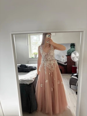 Lång rosa klänning med spetsdetaljer - En super fin balklänning i rosa med broderade blommor och spets. Helt oanvänd med prislapp på. Först till kvarn!