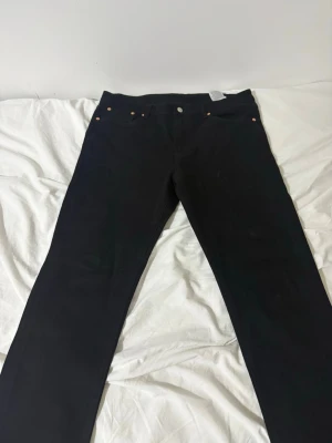 Svarta Levi's jeans raka ben - Säljer ett par svarta jeans från Levi's med klassisk femficksdesign. ikoniska läderpatchen bak i midjan. Perfekta för en clean och stilren look. och har haft dem i en vecka 