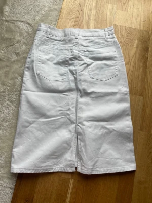 Vit jeanskjol med fickor - Snygg vit jeanskjol. Kjolen har en rak passform och slits bak.