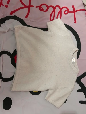 Beige stickad croppad topp - Säljer en beige stickad topp med korta ärmar och rund hals. Modellen är croppad och har en enkel, clean look som passar perfekt till jeans eller kjol. Materialet är mjukt och ger en avslappnad vibe. Köpte för ungefär 249kr