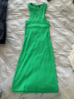 Grön ribbad ärmlös klänning - Snygg grön ribbad klänning i stretchigt material. Modellen är ärmlös med rund halsringning och har en kroppsnära passform. Perfekt för dig som gillar en enkel men trendig look.