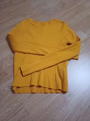 Gul långärmad tröja Divided S - Säljer en snygg gul långärmad tröja från Divided. Tröjan har lång ärm, rund halsringning och är tillverkad i ett mjukt, stretchigt material. Perfekt för lager på lager och ger en poppig färg till din outfit.