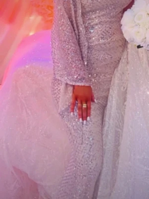 Glittrig långklänning i guld - Säljer en elegant långklänning i guld med glittrigt material och långa ärmar. Klänningen har en figurnära passform och är perfekt för speciella tillfällen. Materialet skimrar vackert i ljuset och ger en lyxig känsla.