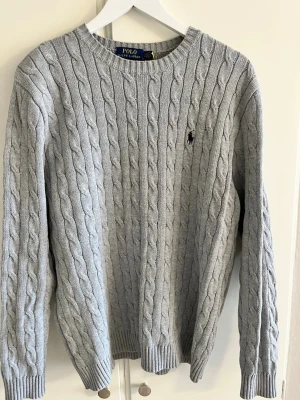 Ralph Lauren tröja - Jag säljer en kabelstickad tröja ifrån Ralph Lauren. Den är i väldigt bra skick, knappast använd. Storlek M, färg grå. Pris kan diskuteras.