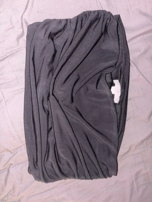 Svart tubtopp från H&M - Säljer en svart tubtopp från H&M. Toppen är axelbandslös med resår upptill och nedtill för att sitta på plats. Materialet är mjukt och stretchigt, perfekt för att styla med olika outfits. Enkel och stilren design.
