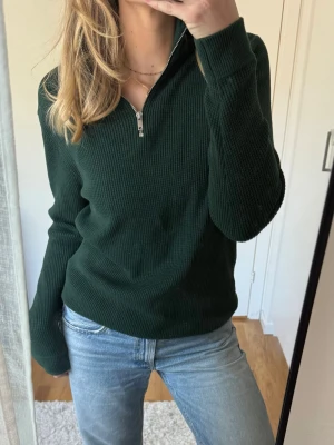 Mörkgrön halfzip-tröja från M&S - Mörkgrön tröja med zip i halsen, långa ärmar och hög krage från M&S. Knappt använd och perfekt till vardags! Funkar både för tjej och kille. 