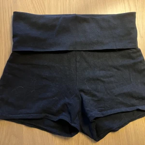 Svarta hotpants med yogamidja - Mysiga svarta shorts med vikbar mudd i  midjan. Tillverkade i mjuk bomull, perfekta för avslappnade dagar eller träning. Klassisk och enkel design utan synliga detaljer eller mönster. Omsydda från Yoga pants från Gina Tricot.