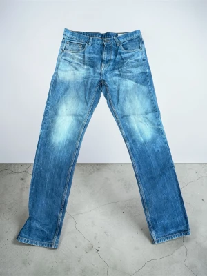Vintage jeans - Säljer ett par klassiska blå jeans med raka ben och tydliga slitningar framtill och baktill. Jeansen har fem fickor och normal midja. Perfekta för en avslappnad och trendig look. Materialet är denim i bomull.