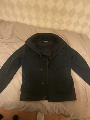 Mörkblå J.Lindeberg field jacket  - Riktigt snygg field jacket från j Lindberg i mycket bra skick. Ser ej något som skiljer den från en ny. Köptes för 3400kr nypris och säljes för 2000!