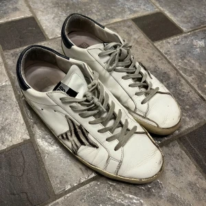 Vita sneakers från Golden Goose - Snygga vita sneakers från Golden Goose, bra men använt skick. 6,5/10. Sulan är sliten och en fläck på hälen. Lite smutsiga men är design samt lätta fläckar som går att tvätta bort. Passar 42. Endast skor medföljer. Hör av er vid funderingar!