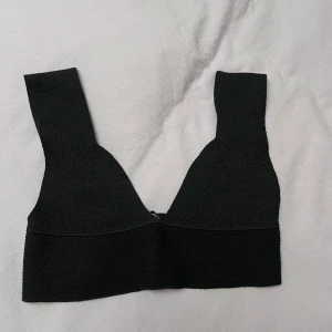 Svart ribbad topp från Missguided - Snygg svart ribbad topp från Missguided. Den har en djup v-ringning och breda axelband. Perfekt för en stilren look.