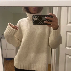 Vit stickad polotröja - Mysig vit stickad polotröja med långa ärmar och ribbade muddar. Perfekt för kyliga dagar och ger en stilren look. Passar bra till både jeans och kjol.
