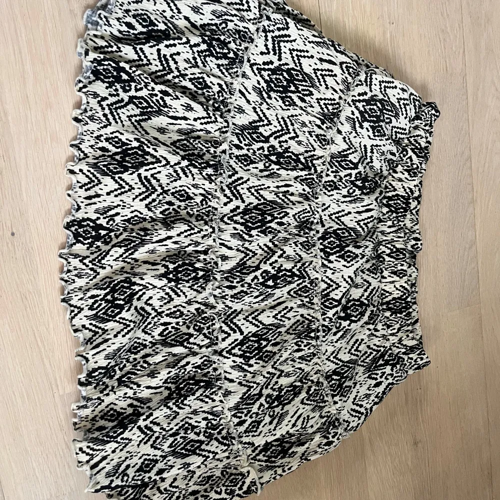 Snygg mönstrad kjol från Lindex i svart och vit. Kjolen har ett elastiskt midjeband för extra komfort och ett trendigt geometriskt mönster. Perfekt för att ge din outfit en unik touch! . Hameet.