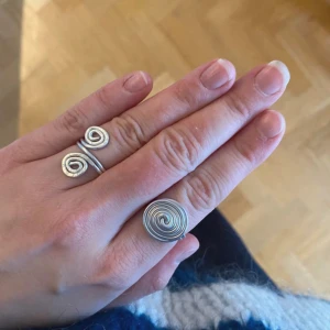2 ringar silver💍 - Två unika ringar i silverfärg med spiraldesign. Den ena ringen har en större spiral medan den andra har två mindre spiraler. Perfekta för att ge en stilfull touch till din look.