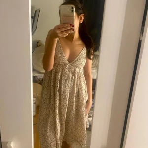 Blommig sommarklänning - Söt blommig klänning med v-ringning och tunna axelband. Perfekt för varma sommardagar. Den har en luftig passform och är gjord i ett lätt material som ger en skön känsla. Klänning är i mycket bra skick.