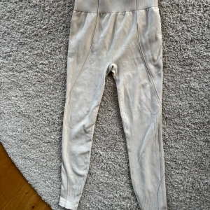 Beige leggings från H&M Move - Snygga beige leggings från H&M Move med hög midja och ribbade detaljer. Perfekta för en bekväm och stilren look. Tillverkade i ett mjukt och stretchigt material som ger en skön passform.