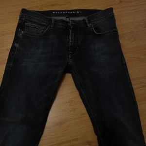 Mörkblå jeans från Baldessarini - Snygga mörkblå jeans från Baldessarini med regular fit. Klassisk design med fem fickor och diskret broderi på bakfickorna. Perfekta för en stilren look.