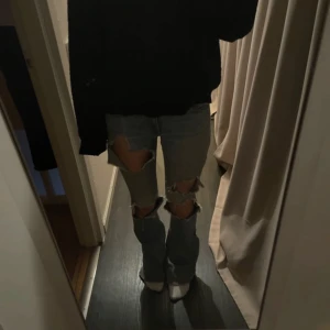 Ljusa slitna jeans  - Säljer ett par ljusa jeans med slitningar på knäna och låren. De har en bootcut-stil och är perfekta för en avslappnad look. Jeansen har klassiska fem fickor och en knappgylf. Dem är lite upptrampade men inget man ser på mig, jag är 164. Pris kan diskuteras 