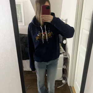 Mörkblå hoodie från ralph lauren - Säljer en snygg mörkblå hoodie från Polo Ralph Lauren med ett stort broderat polomotiv på framsidan. Använd väldigt fåtal gånger och det står storlek L men skulle säga S