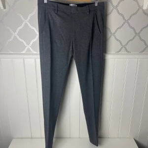 Grå kostymbyxor från Dondup - Snygga grå kostymbyxor från Dondup med en stilren design. Byxorna har en midwaist passform och är utrustade med knappar bak. Perfekta för en elegant look.