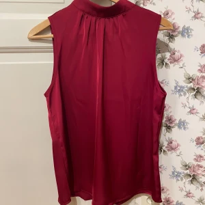 Röd ärmlös topp - Snygg röd ärmlös topp med hög krage. Perfekt för en stilren look. 