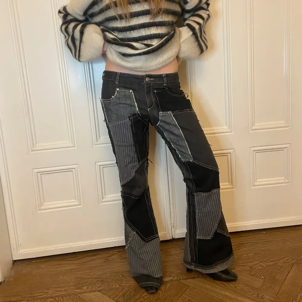 Snygga patchwork jeans med en mix av svarta och gråa paneler. Byxorna har en bootcut-stil och är dekorerade med kontrasterande sömmar. Perfekta för dig som vill sticka ut med en unik look. Får alltid komplimanger när jag har på mig dem här! Köpta second hand!. Farkut & Housut.