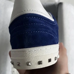 Valentino flycrews - Snygga sneakers från Valentino i blå mocka med vita detaljer. Skorna har en klassisk design med snörning och dekorativa nitar på sulan. Perfekta för en stilren look, storlek 43