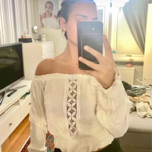 Vit blus - Säljer en söt vit offshoulder/justerbar blus med spetsdetaljer framtill. Blusen har långa ärmar och en luftig passform.