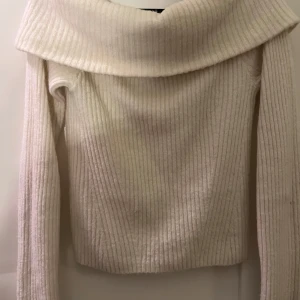 Vit ribbad offshoulder tröja - Säljer en stilren vit ribbad offshoulder tröja med långa ärmar. Perfekt för en elegant och avslappnad look. Tröjan har en bred krage som ger en unik touch. Passar bra till både jeans och kjol.